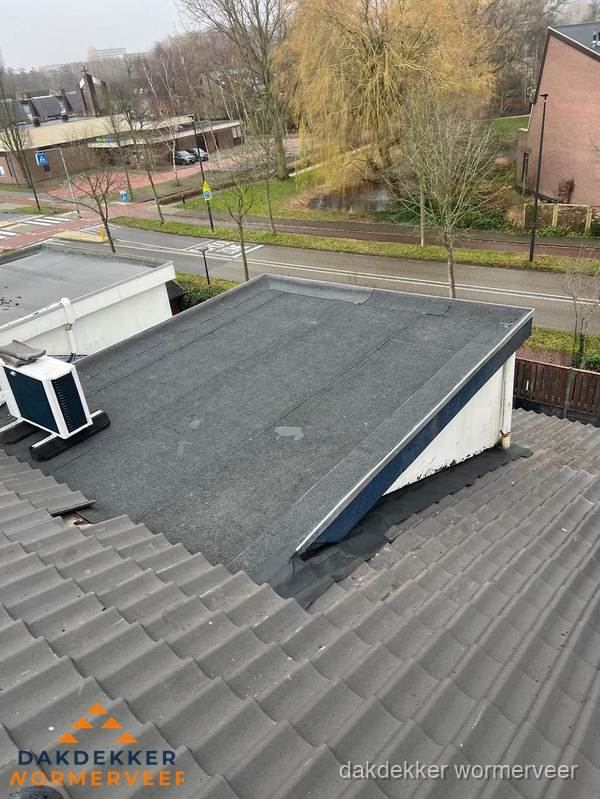 Plat dak met bitumen dakbedekking naast schuin pannendak in Wormerveer