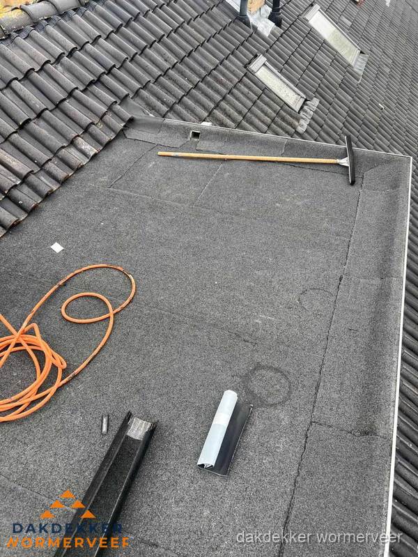 Plat dak reparatie met gereedschap en loodstroken in Wormerveer