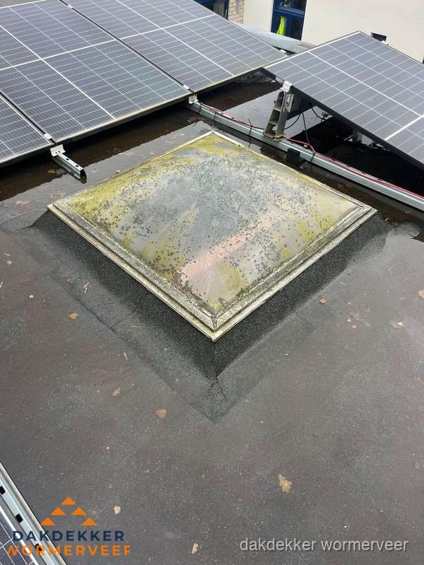 Vervuilde lichtkoepel op plat dak met zonnepanelen in Wormerveer
