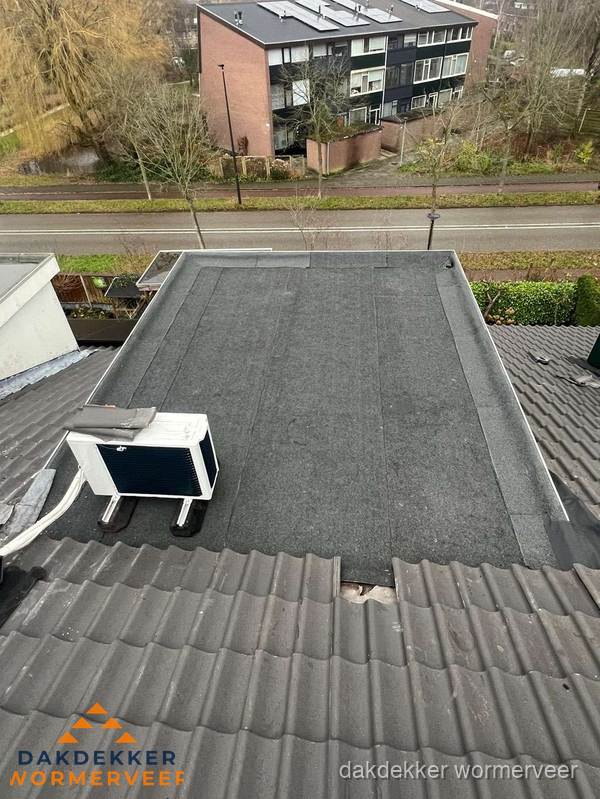 Plat dak inspectie met bitumen bedekking naast schuin pannendak in Wormerveer