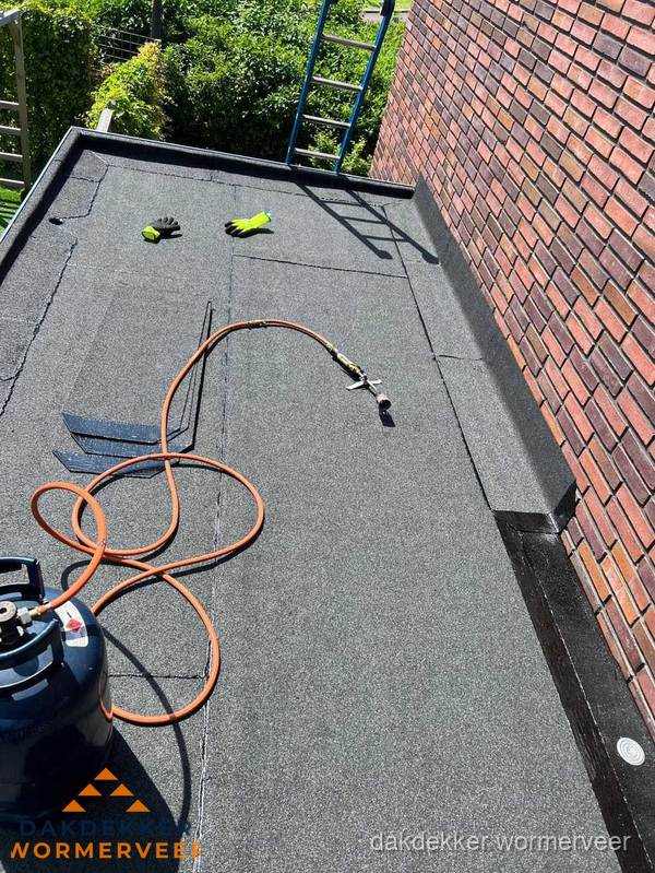 Plat dak met bitumen en brandgereedschap van dakdekkersbedrijf in Wormerveer