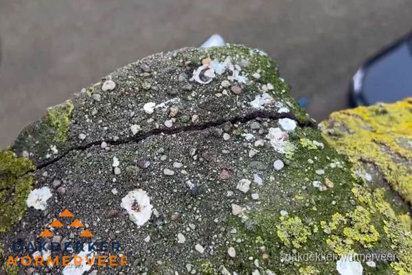 Beschadigde en verweerde nokvorst met scheuren en mos in Wormerveer