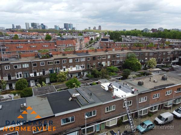 Spoed dakdekker aan het werk op plat dak in woonwijk Wormerveer