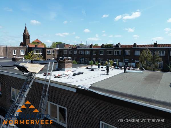 Dakdekkers aan het werk op plat dak in Wormerveer