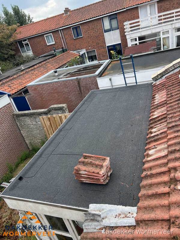 Plat dak aanbouw met bitumen naast schuin pannendak in Wormerveer