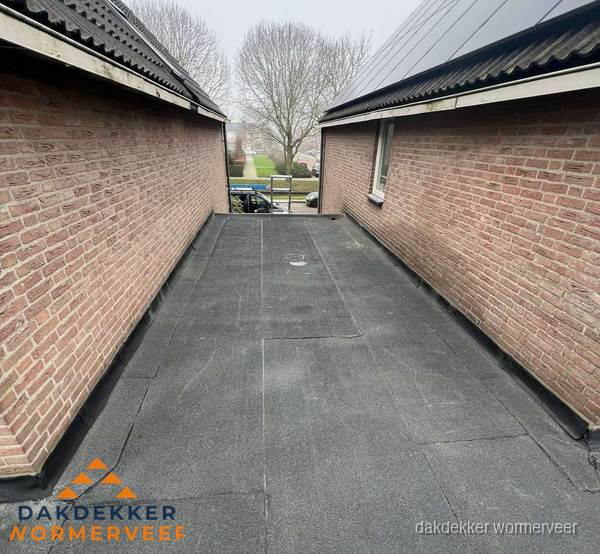 Plat dak met bitumen dakbedekking tussen bakstenen muren in Wormerveer